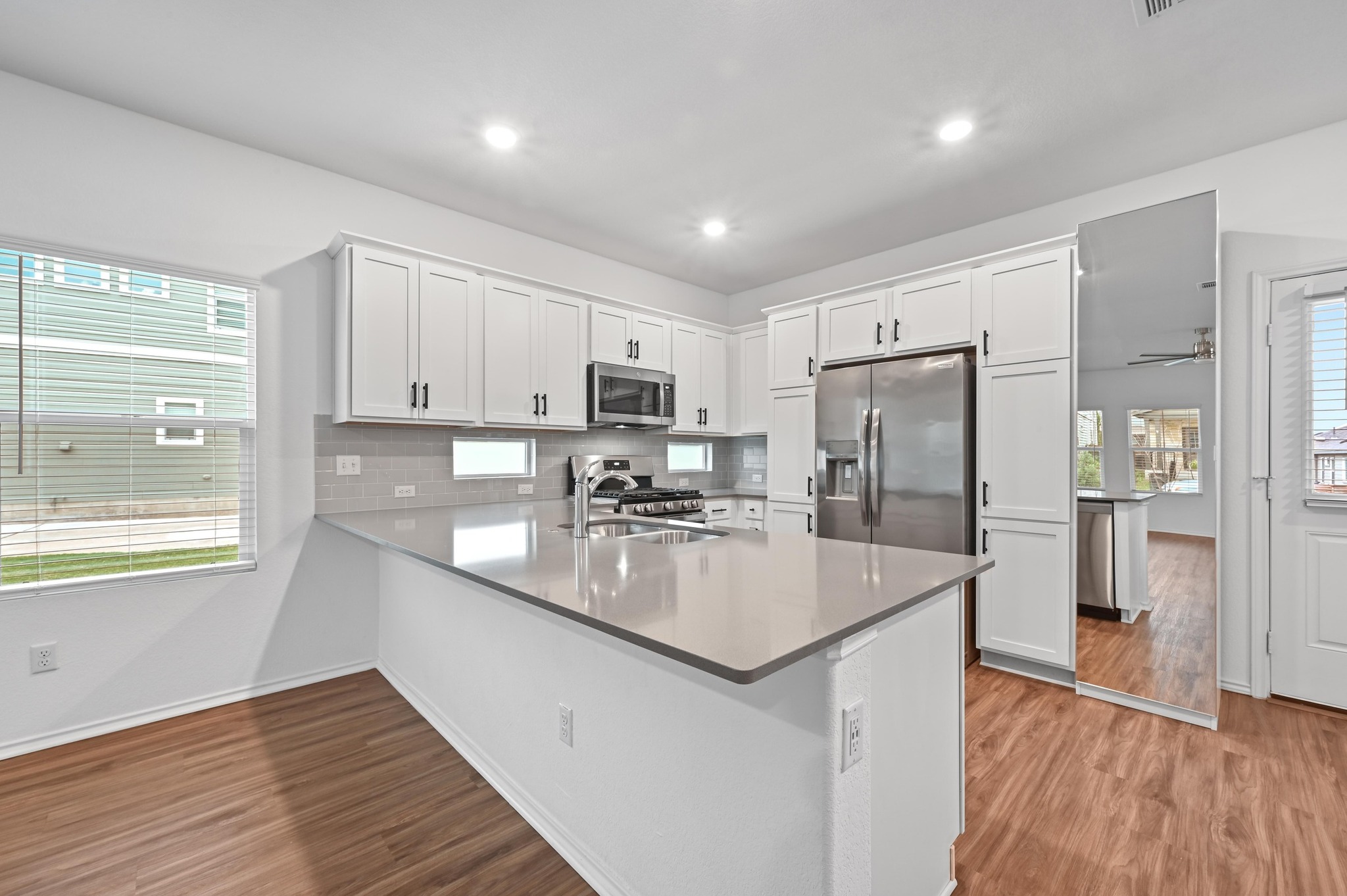 167 Rioja, Unit MAIN HOUSE) Kyle, TX 78640 - Photo 11 of 26 Kitchen with white cabinetry, appliances with stainless steel finishes, a peninsula, tasteful backsplash.
