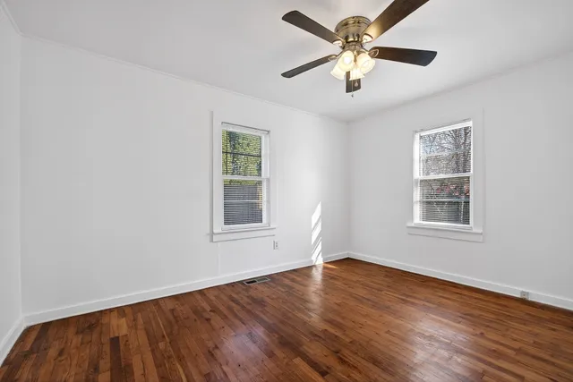 a view of an empty room with window and wooden floor