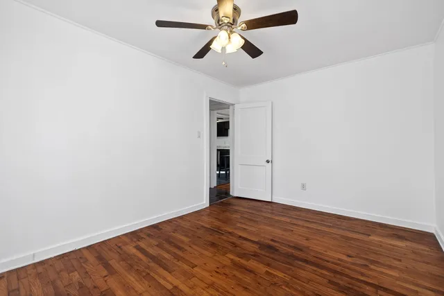 an empty room with wooden floor ceiling fan and window