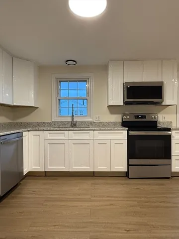 a kitchen with granite countertop a stove a sink and a microwave