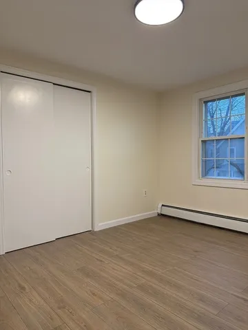 a view of an empty room with a window and wooden floor