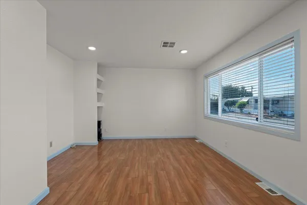 a view of empty room with wooden floor and fan