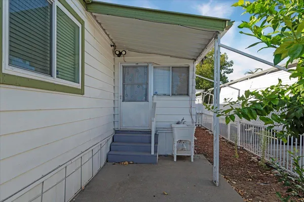 a view of house with wooden fence and large trees
