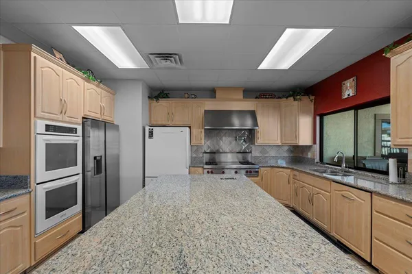 a kitchen with stainless steel appliances granite countertop a sink a stove and a refrigerator