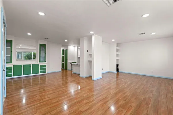 a view of an empty room with wooden floor and windows