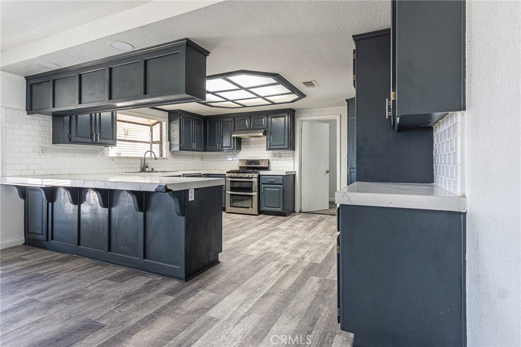 13114 Choco Road Apple Valley, CA 92308 - Photo 18 of 75 a kitchen with stainless steel appliances granite countertop a stove a sink and a microwave