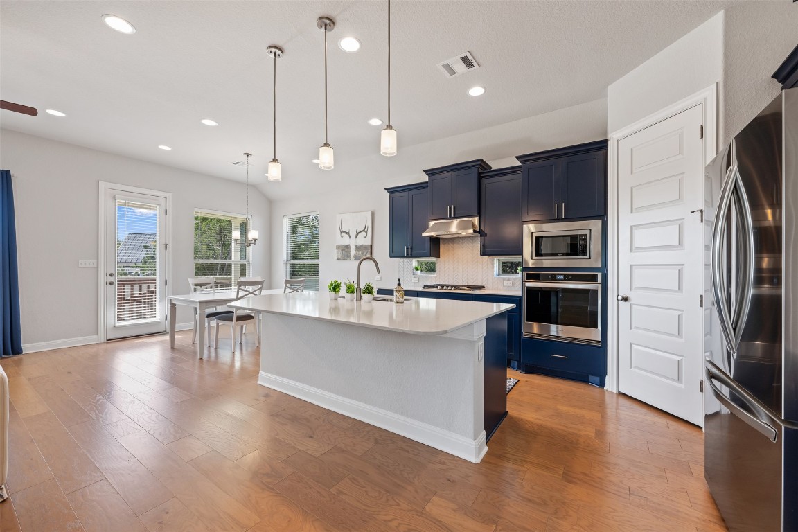 686 Treadwell Lane Kyle, TX 78640 - Photo 11 of 40 a kitchen with stainless steel appliances kitchen island granite countertop a refrigerator and a stove top oven
