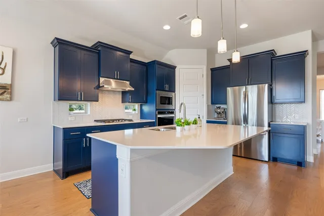 a large kitchen with stainless steel appliances wooden cabinets a center island a stove and a refrigerator