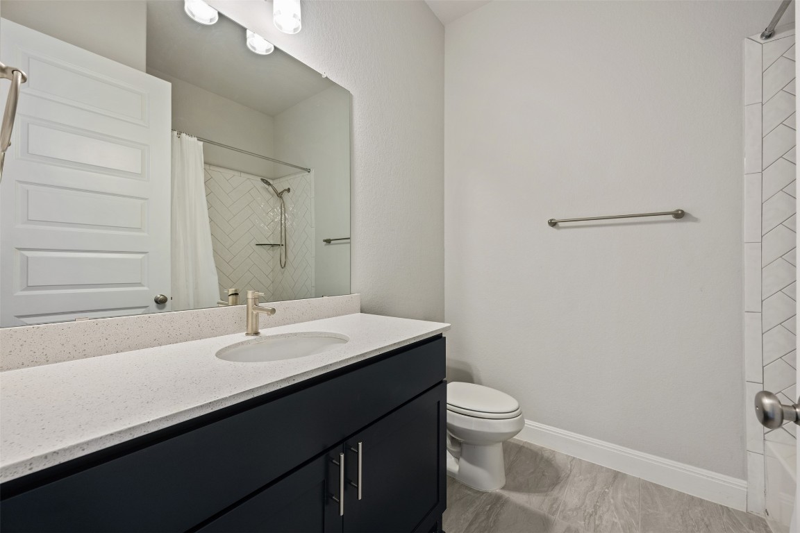 686 Treadwell Lane Kyle, TX 78640 - Photo 32 of 40 a bathroom with a sink a toilet a light fixture and a mirror