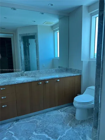 a bathroom with a granite countertop sink and a toilet