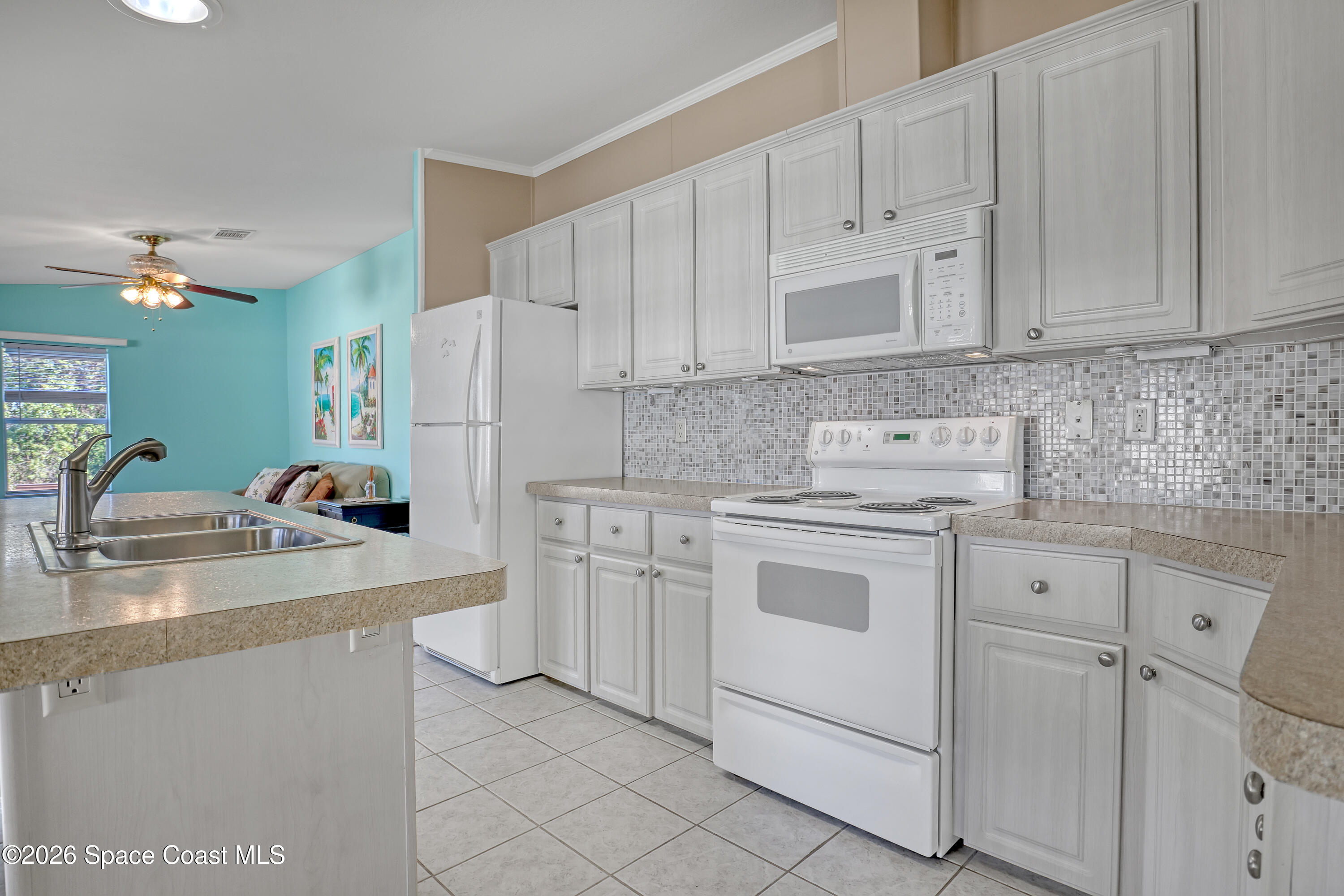 7547 Boxelder Road Micco, FL 32976 - Photo 14 of 53 a kitchen with white cabinets and white appliances