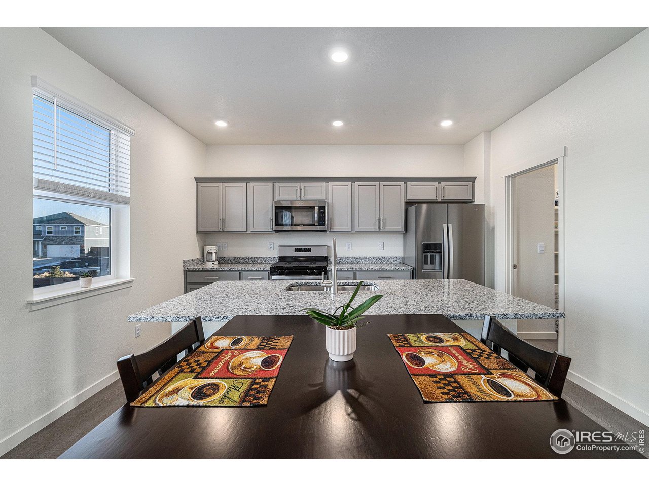 439 Bluebird Road Johnstown, CO 80534 - Photo 15 of 37 a kitchen with stainless steel appliances granite countertop a refrigerator a stove and a sink with wooden floor