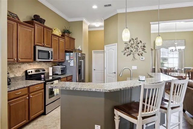 a kitchen with granite countertop a stove a sink dishwasher a dining table and chairs with wooden floor