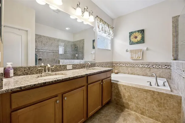 a bathroom with a granite countertop bathtub a double vanity sink a vanity and a large mirror