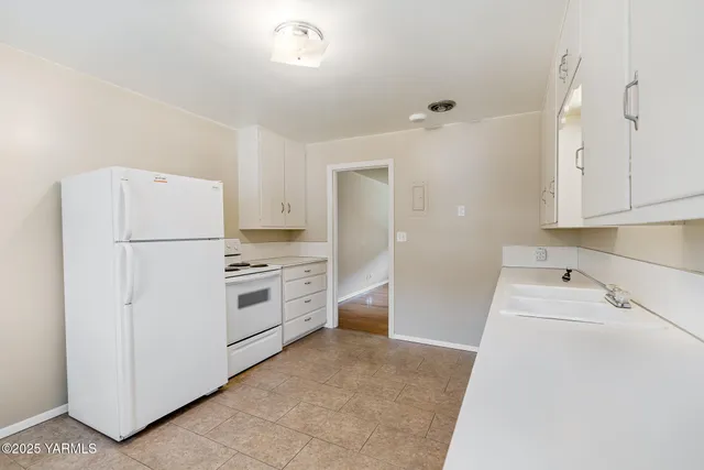 a kitchen with a refrigerator a stove and white cabinets