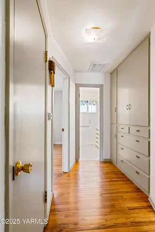 a view of a hallway with wooden floor and closet area