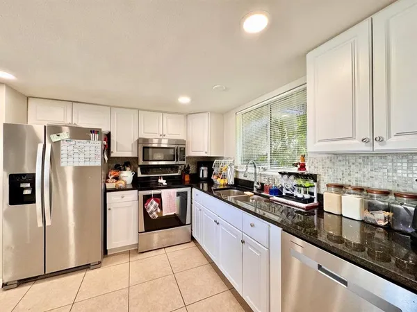 a kitchen with stainless steel appliances granite countertop a refrigerator sink and stove