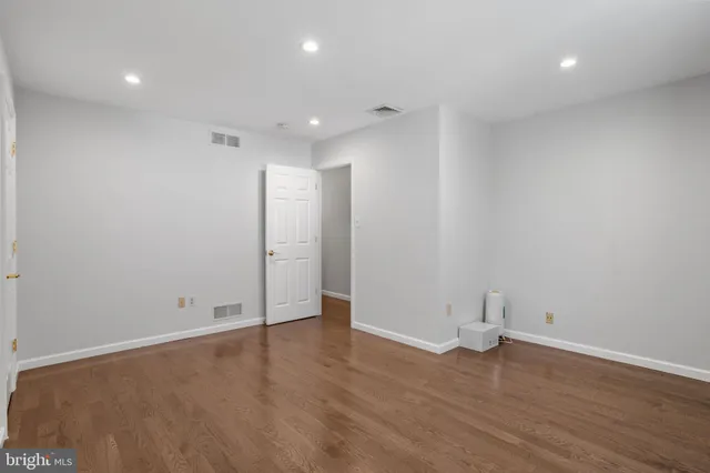 an empty room with wooden floor and bathroom