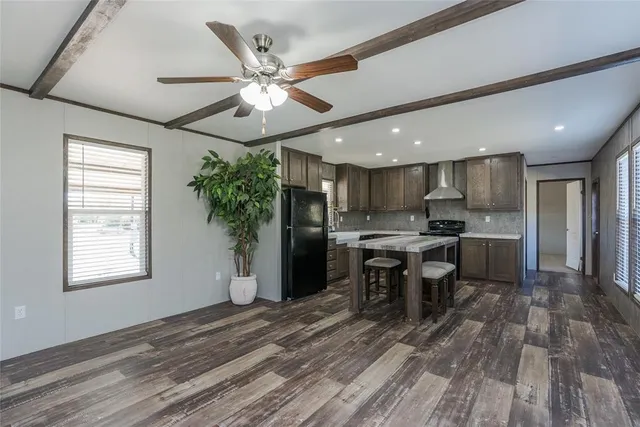 a kitchen with stainless steel appliances granite countertop a refrigerator a stove a sink dishwasher and a dining table with wooden floor