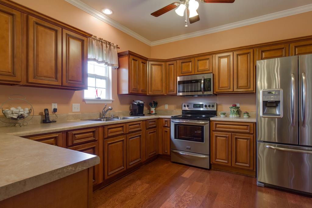 403 Coker Ford Road Portland, TN 37148 - Photo 8 of 29 a kitchen with stainless steel appliances granite countertop a stove top oven a sink and dishwasher a refrigerator with wooden floor