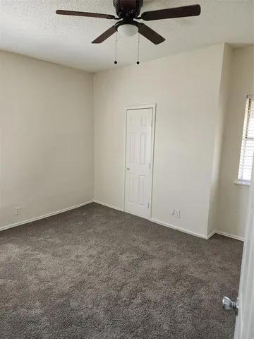 an empty room with a ceiling fan and window