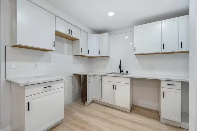 a kitchen with granite countertop white cabinets and a sink