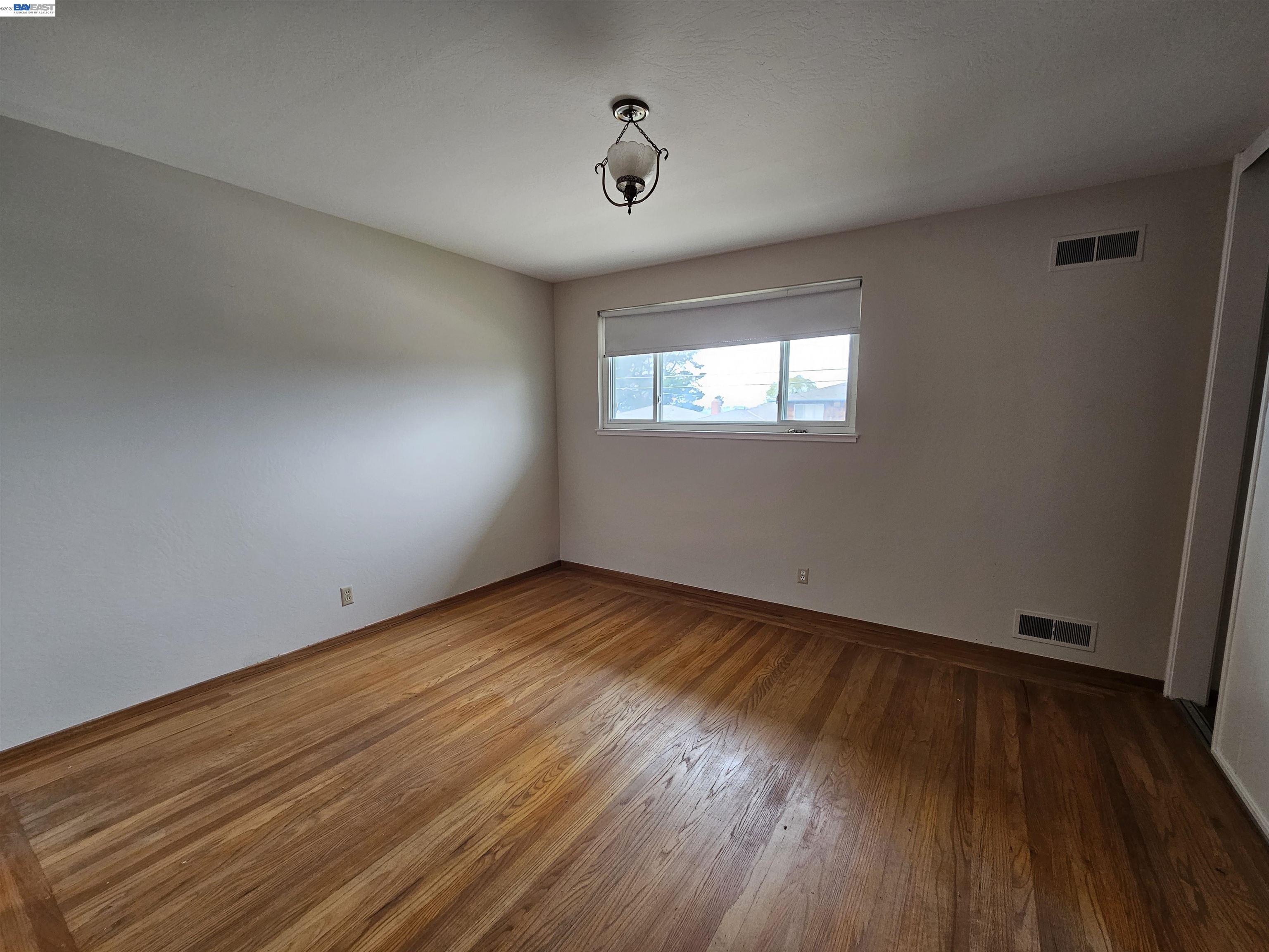 18758 Crane Avenue Castro Valley, CA 94546 - Photo 6 of 13 an empty room with wooden floor and windows