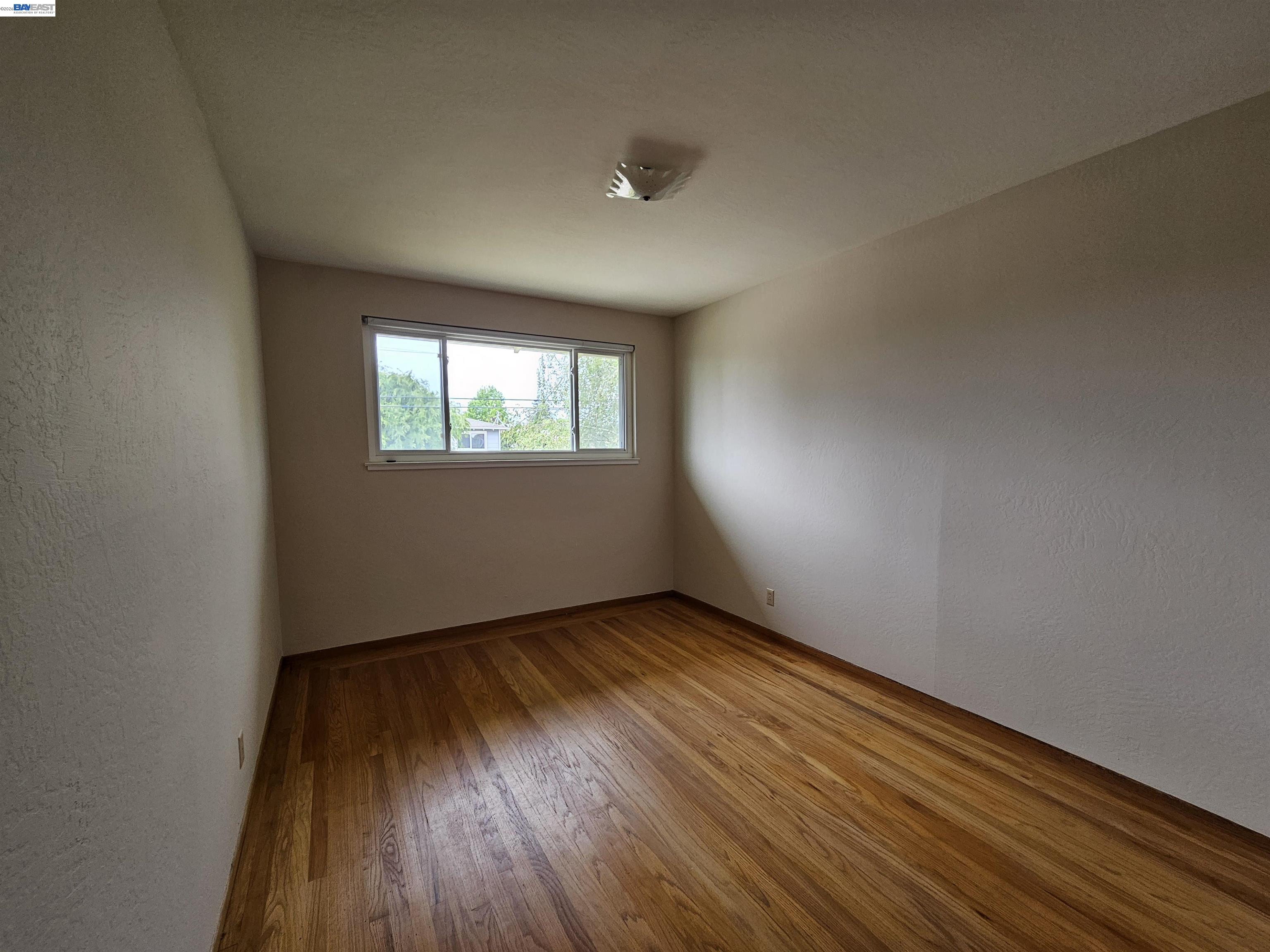 18758 Crane Avenue Castro Valley, CA 94546 - Photo 9 of 13 an empty room with wooden floor and windows