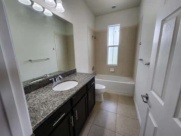 a spacious bathroom with a granite countertop sink a mirror and a bathtub