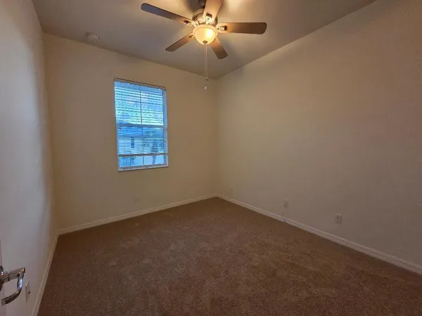 an empty room with windows and fan