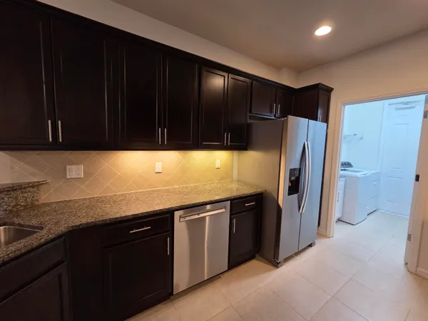 a kitchen with stainless steel appliances granite countertop a refrigerator and a stove top oven