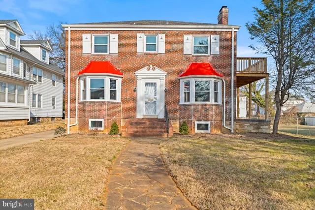 a view of a white house with large windows and a small yard