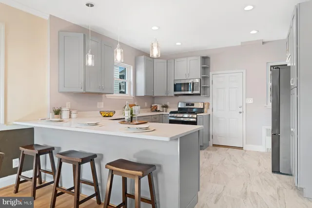 a kitchen with stainless steel appliances granite countertop a sink a stove a refrigerator and island with wooden floor