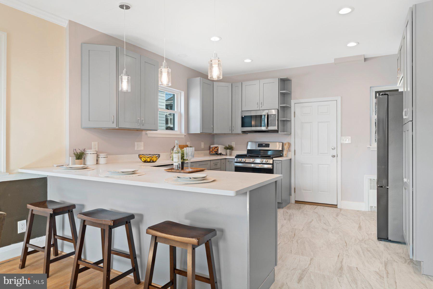 3704 Egerton Road Baltimore, MD 21215 - Photo 8 of 32 a kitchen with stainless steel appliances granite countertop a sink a stove a refrigerator and island with wooden floor