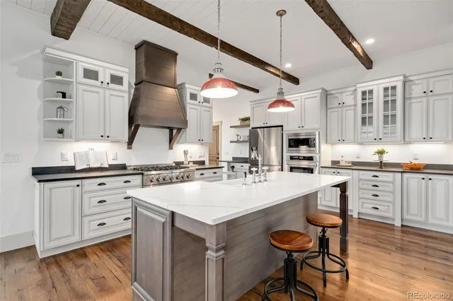 a large kitchen with stainless steel appliances granite countertop a lot of counter space cabinets and a wooden floor