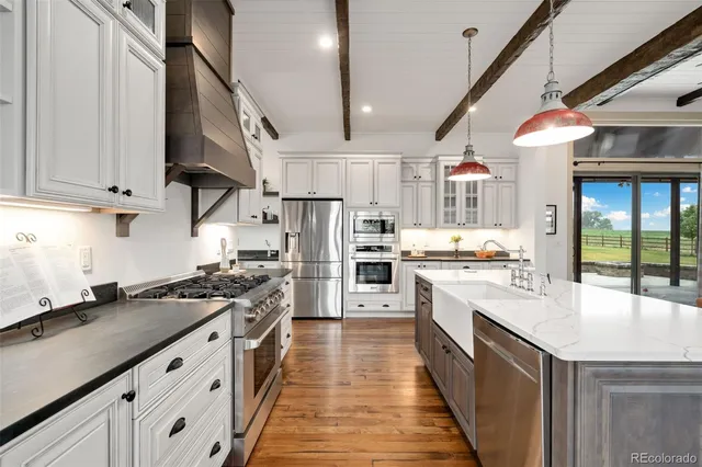 a open kitchen with stainless steel appliances granite countertop a stove a sink dishwasher and white cabinets with wooden floor
