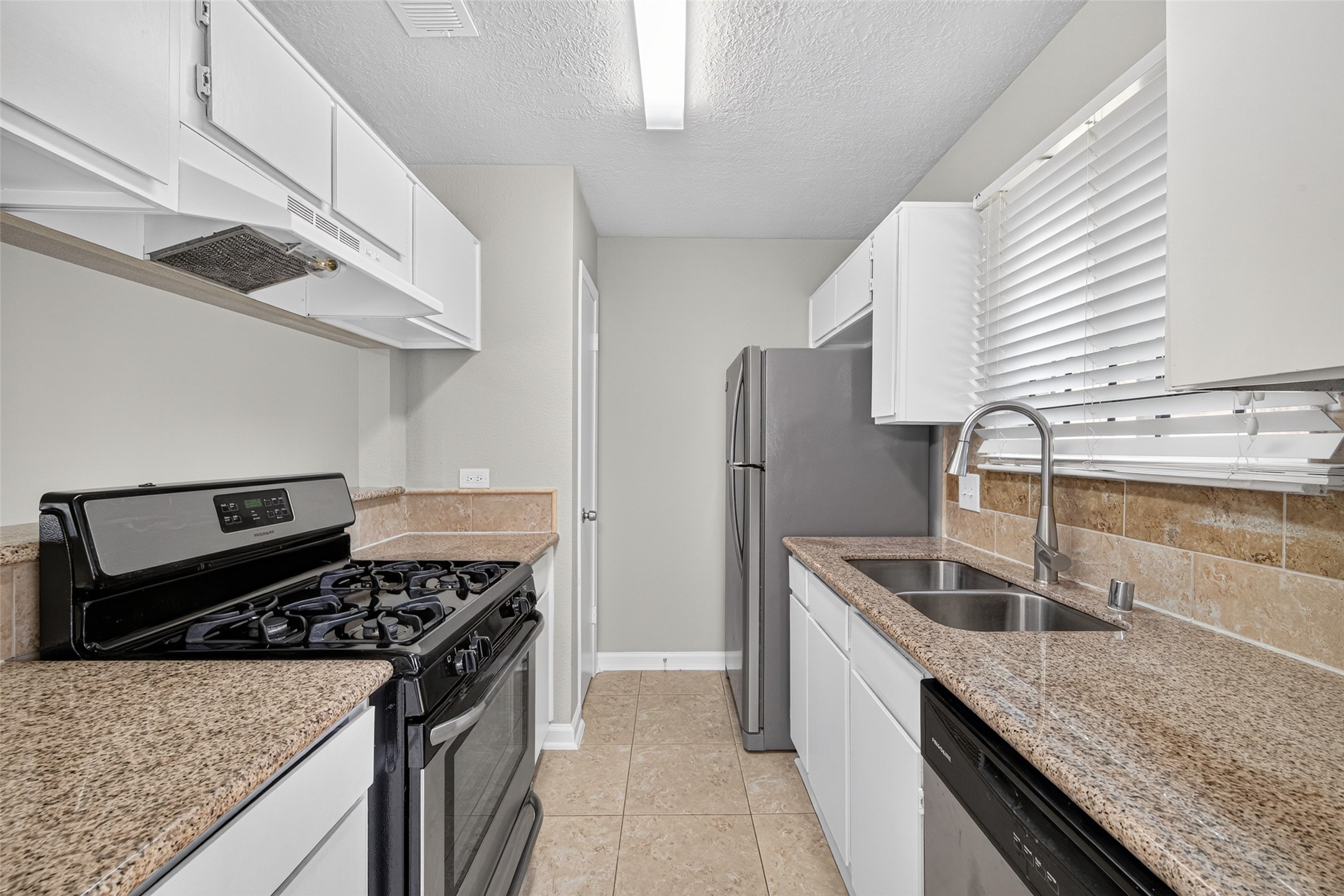 16203 Beck Ridge Drive Houston, TX 77053 - Photo 12 of 29 Modern galley kitchen with sleek granite countertops, stainless steel appliances, and abundant natural light from the large window.