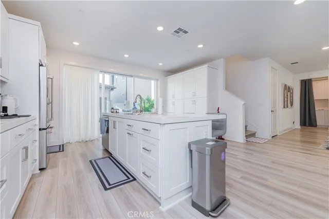 a kitchen with kitchen island granite countertop a refrigerator and a sink