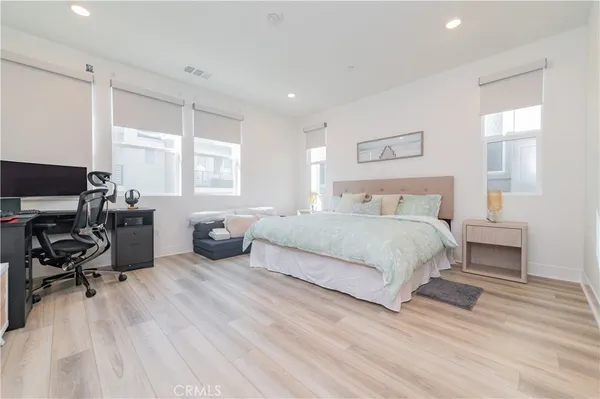 a bedroom with a bed a table and a dresser next to a window