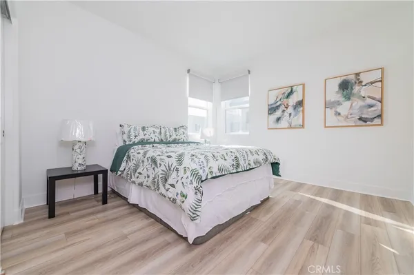 a bedroom with a bed paintings on the wall and a window