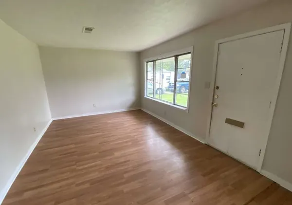 an empty room with wooden floor and windows