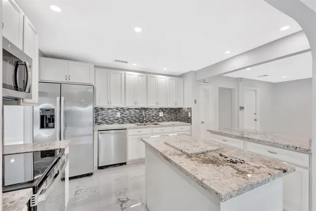 a kitchen with stainless steel appliances granite countertop a refrigerator and a stove top oven