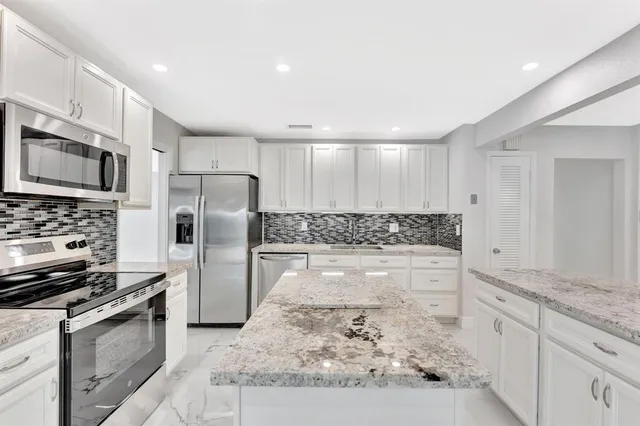 a kitchen with stainless steel appliances granite countertop a stove a microwave and a sink