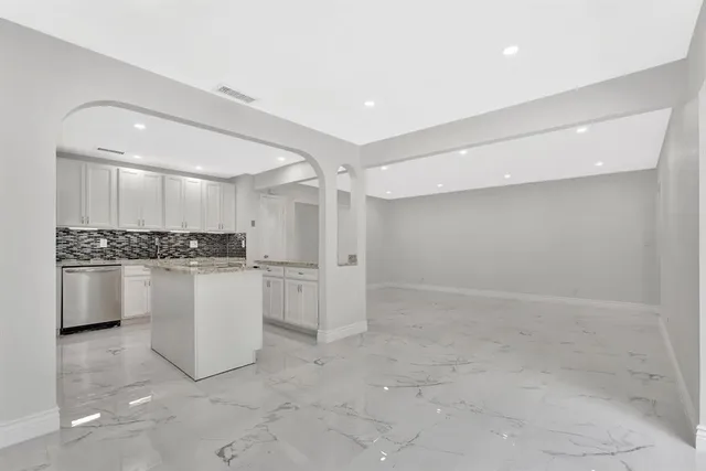 a view of empty room with kitchen and window