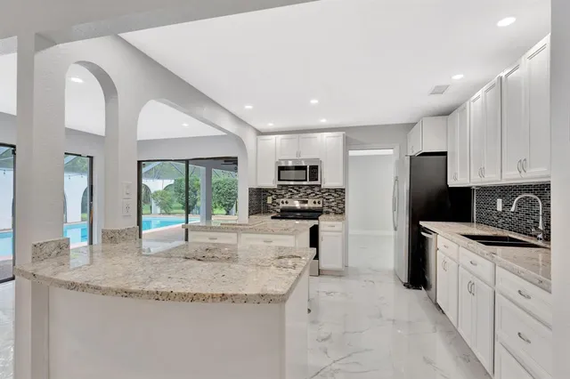 a kitchen with granite countertop a sink stainless steel appliances and white cabinets