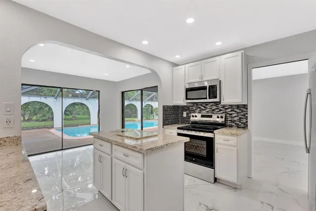 a kitchen with granite countertop a stove top oven microwave and cabinets