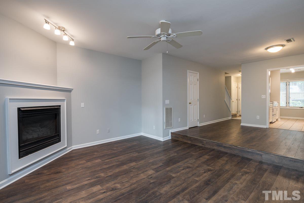 4213 Sunshadow Lane Raleigh, NC 27613 - Photo 5 of 20 an empty room with wooden floor fireplace and windows