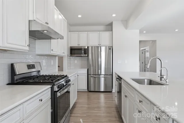 a kitchen with stainless steel appliances a sink a stove a refrigerator and cabinets