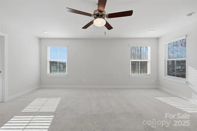 an empty room with windows and ceiling fan