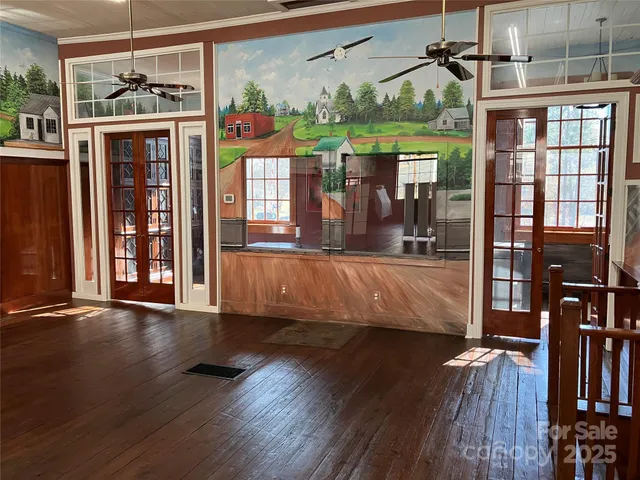a view of a living room with wooden floor and windows